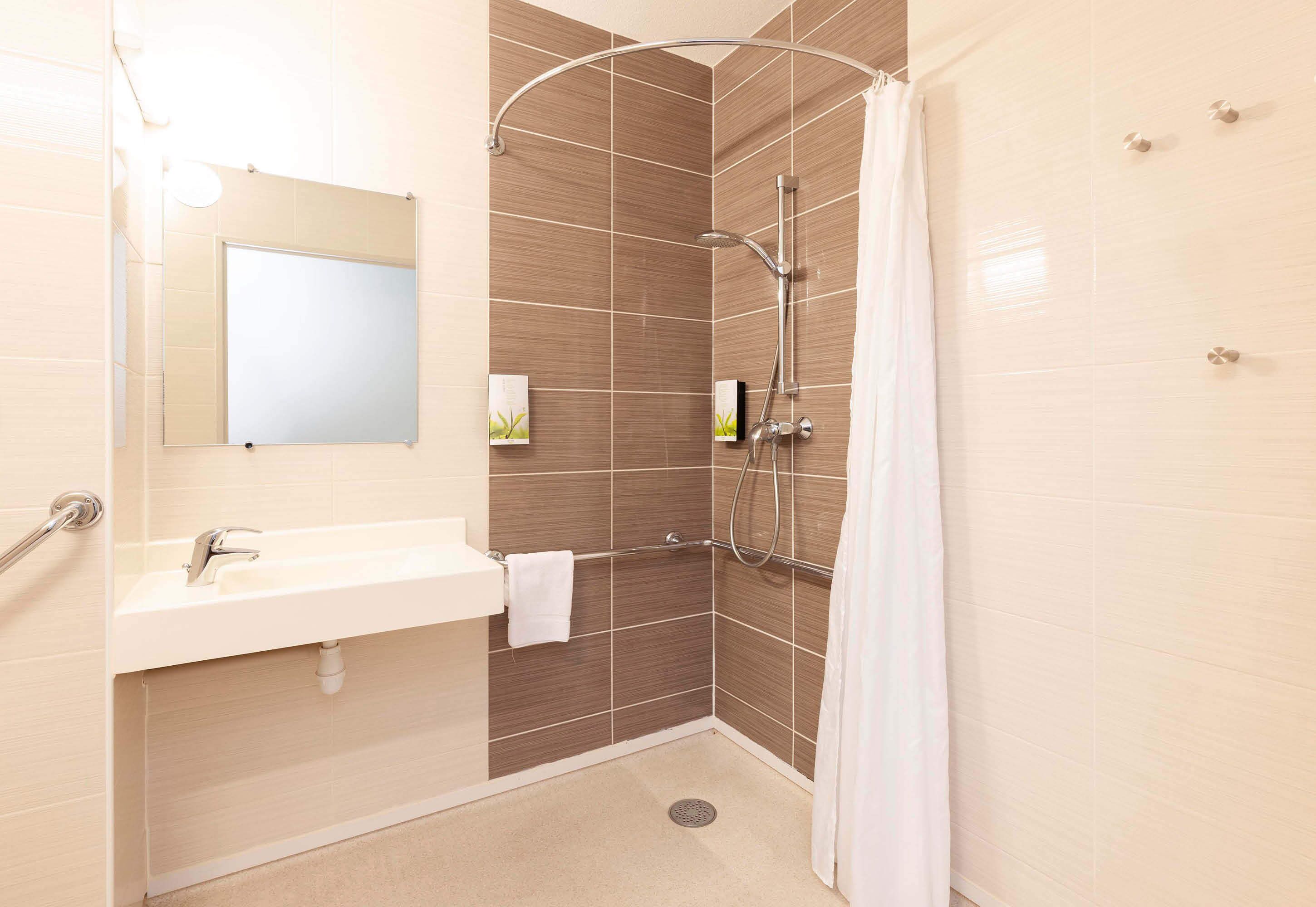Un baño moderno con ducha, lavabo y espejo.