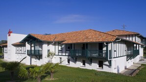A two-story building with a tiled roof, white walls, and green balconies. - B&B HOTEL Saint-Jean de Luz (Saint-Jean-de-Luz)