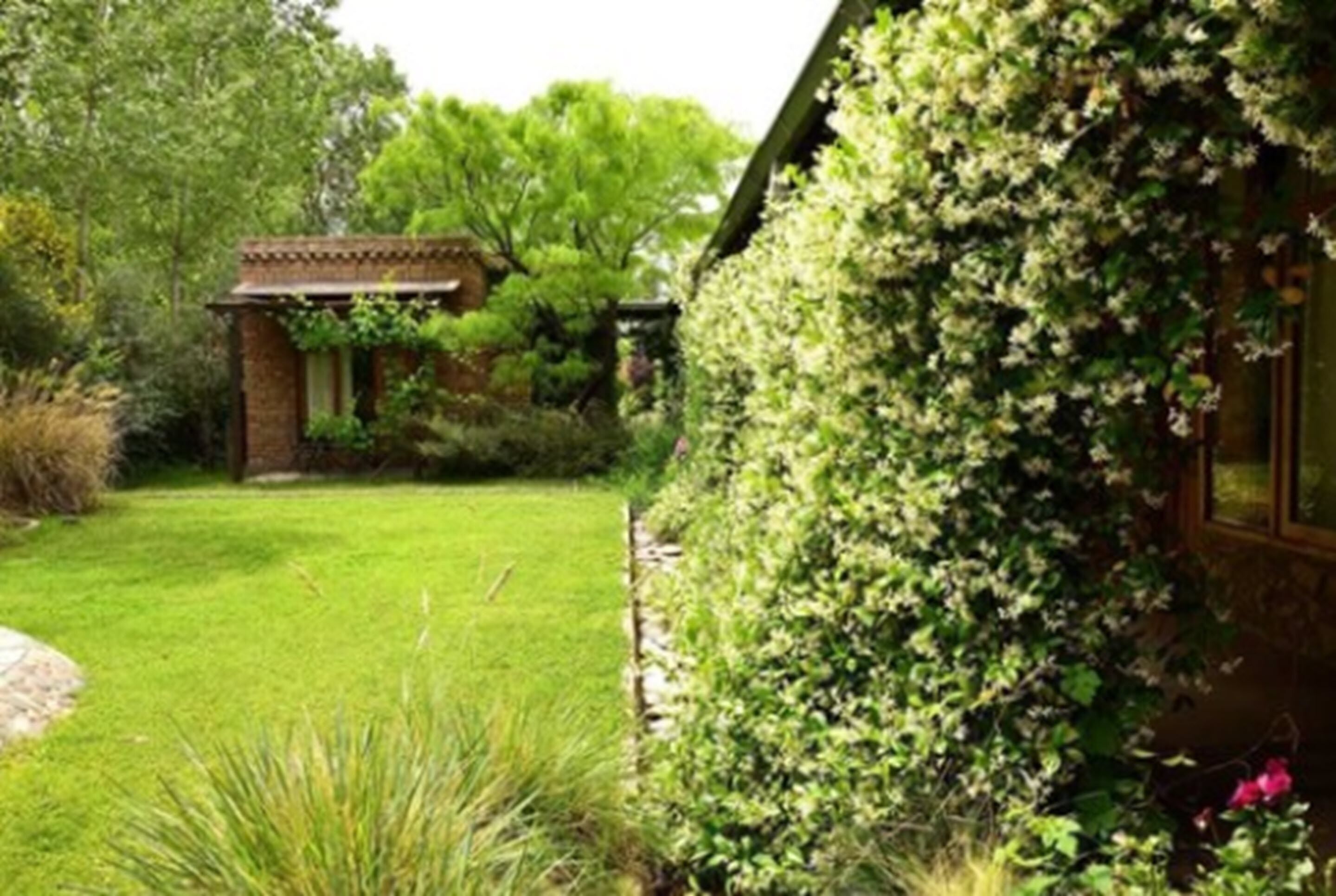 A garden with a brick structure, lush greenery, and a well-maintained lawn.