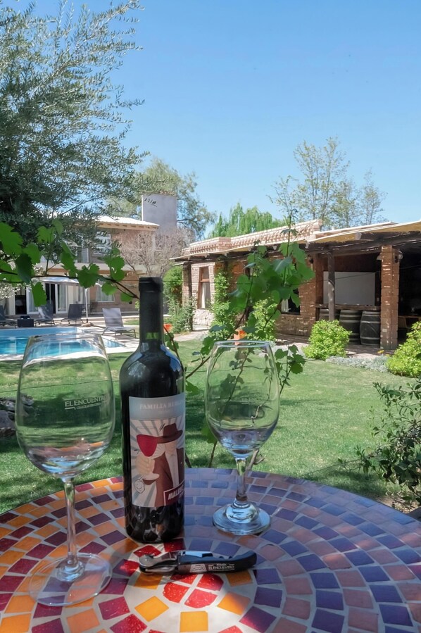 A patio with a mosaic table, a wine bottle, and two wine glasses.