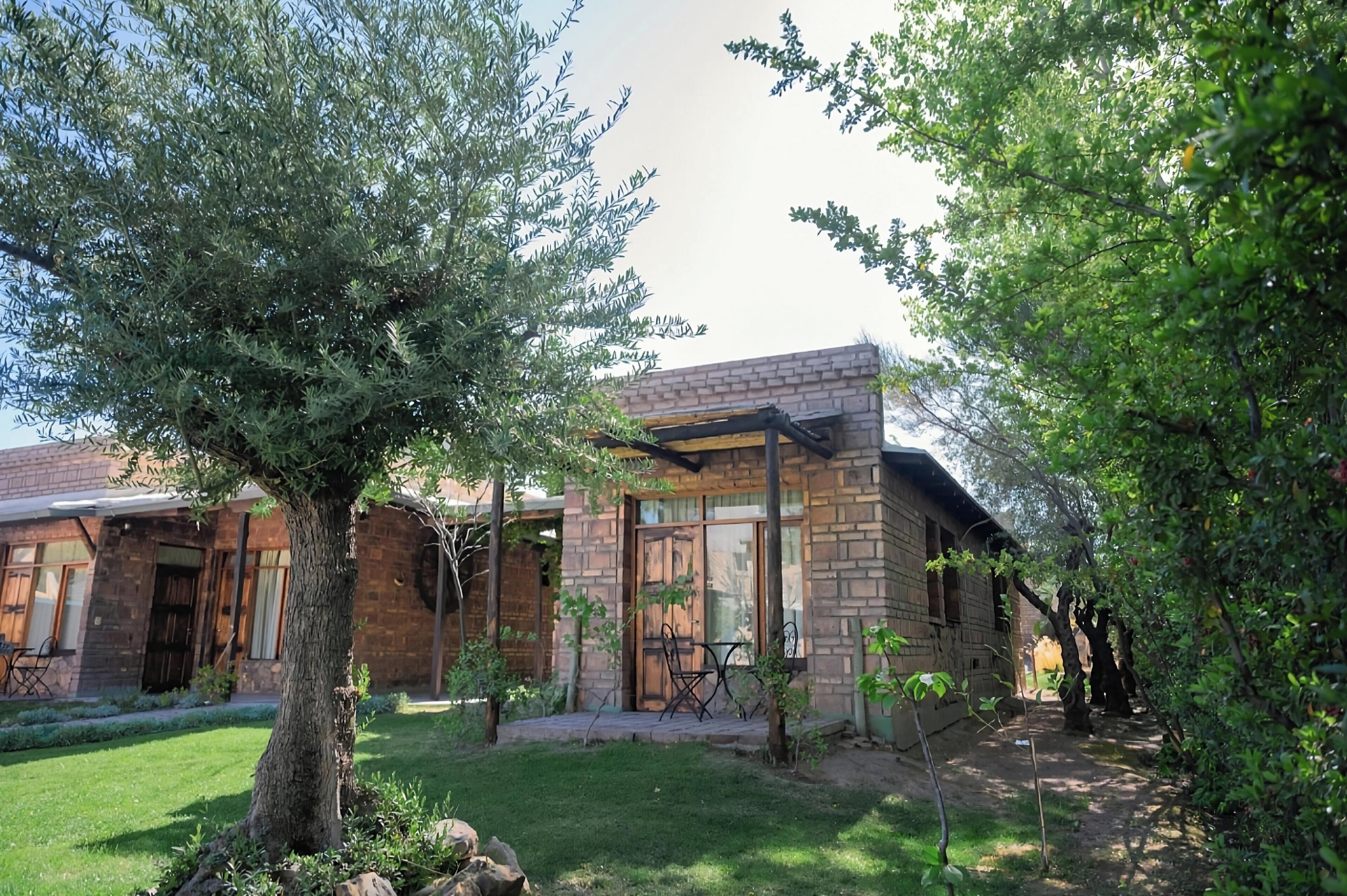 A rustic brick building with a covered patio and a large tree in the foreground.
