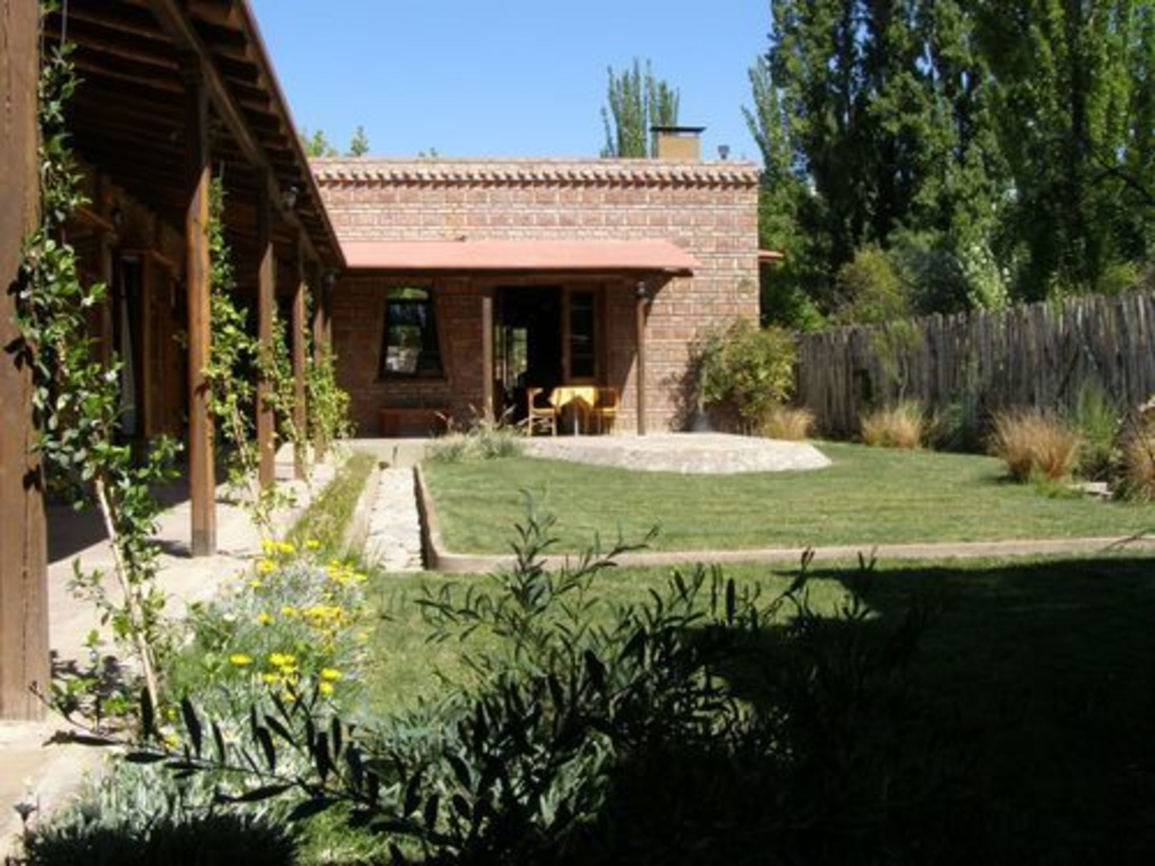 Una casa de ladrillo con porche cubierto y un pequeño jardín.