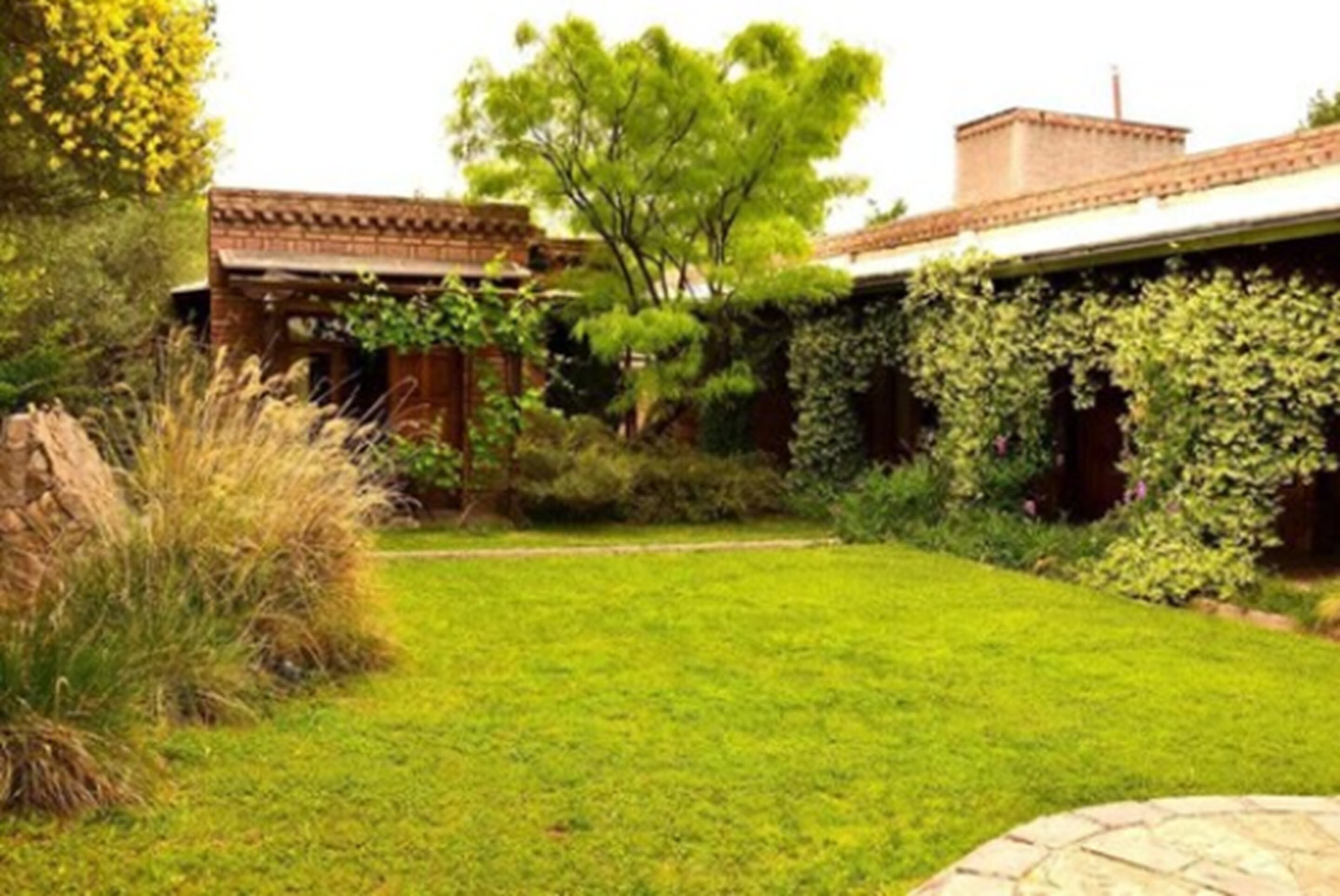 Un jardín bien cuidado con césped, una estructura de ladrillo y plantas trepadoras.
