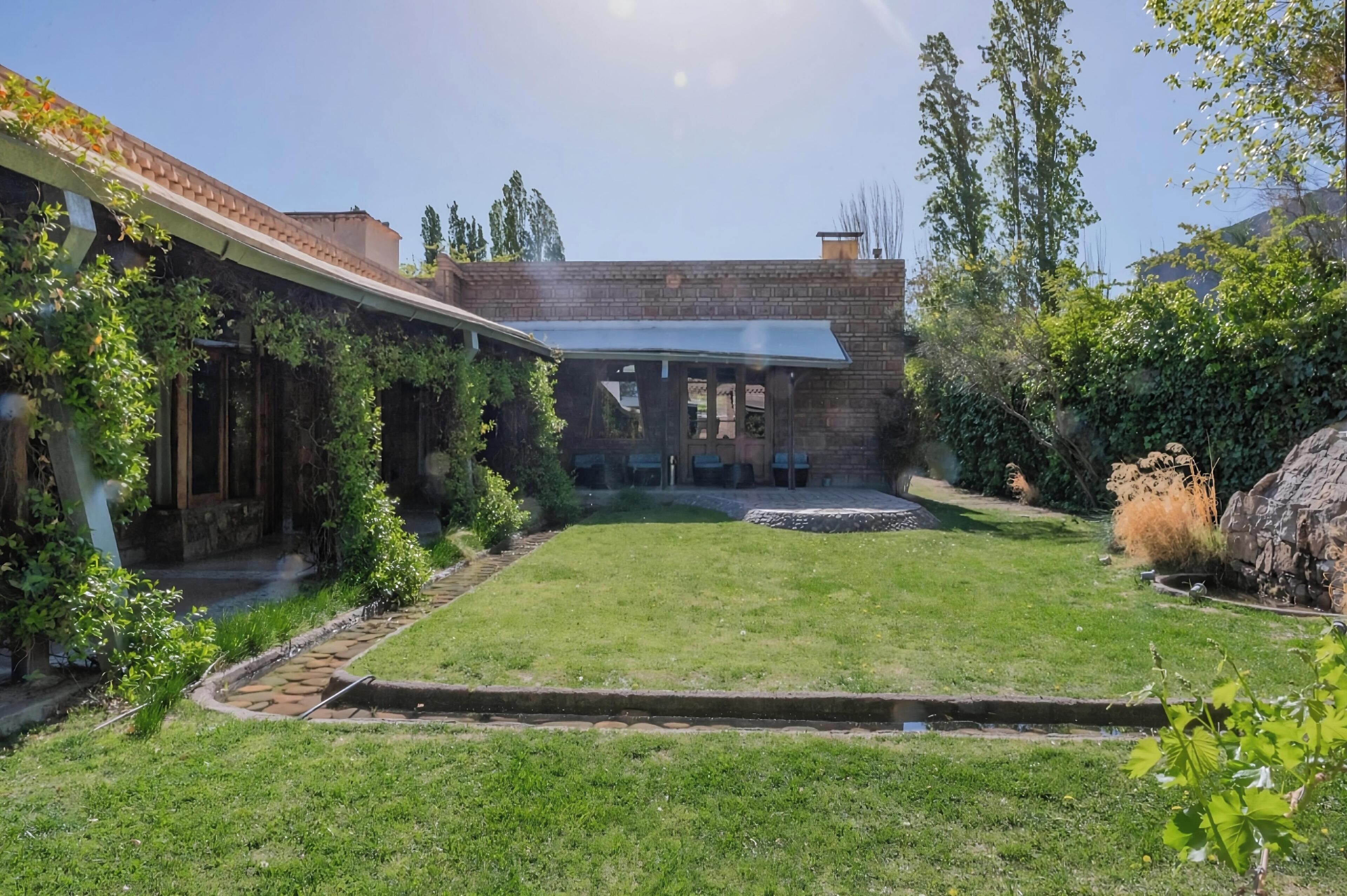 Una casa con fachada de ladrillo, un patio cubierto y un césped bien cuidado.