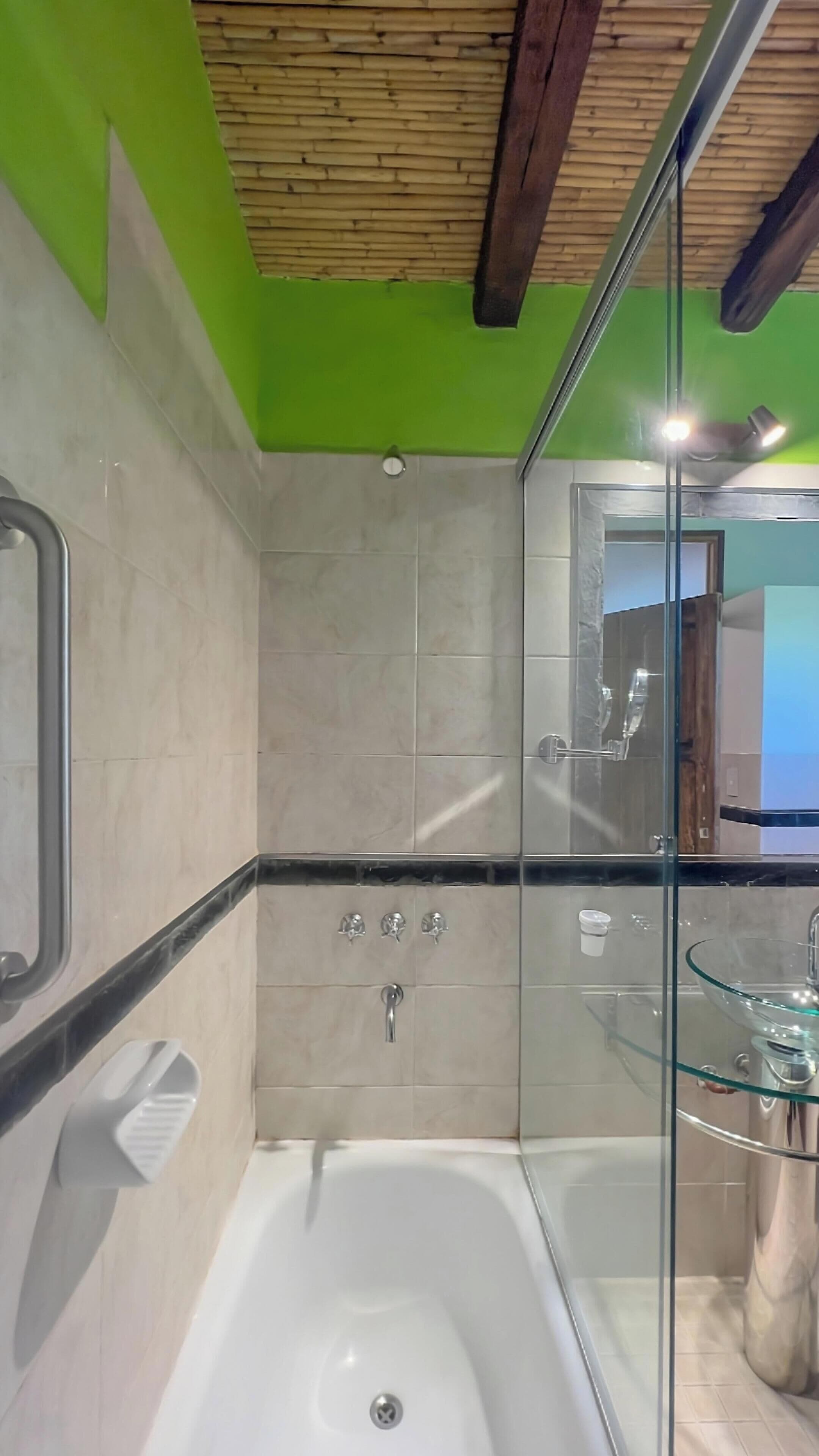 Un baño moderno con ducha de vidrio, bañera y lavamanos de vidrio.