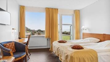 Habitación de hotel con una cama, un escritorio con silla, una ventana con cortinas y vistas al exterior.