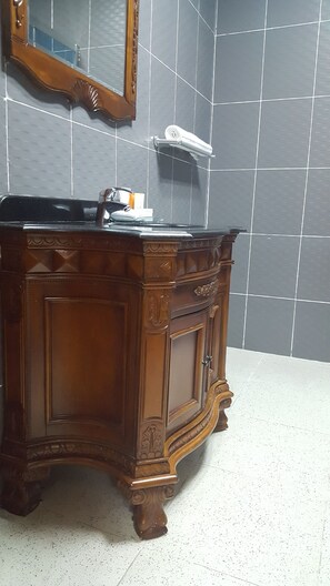 A wooden vanity with a mirror above it, set against a tiled wall.