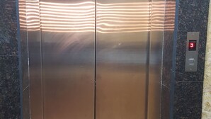 Un ascensor con acabado metálico y una pantalla digital que muestra el número 3.