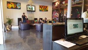 Zona de recepción de hotel con diseño moderno, que incluye un mostrador de recepción, área de estar con sofás y obras de arte en las paredes.