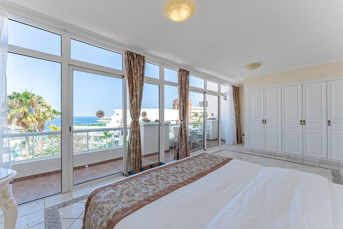 Ein Schlafzimmer mit einem großen Bett, einem Balkon mit Meerblick und einer Schiebetür.