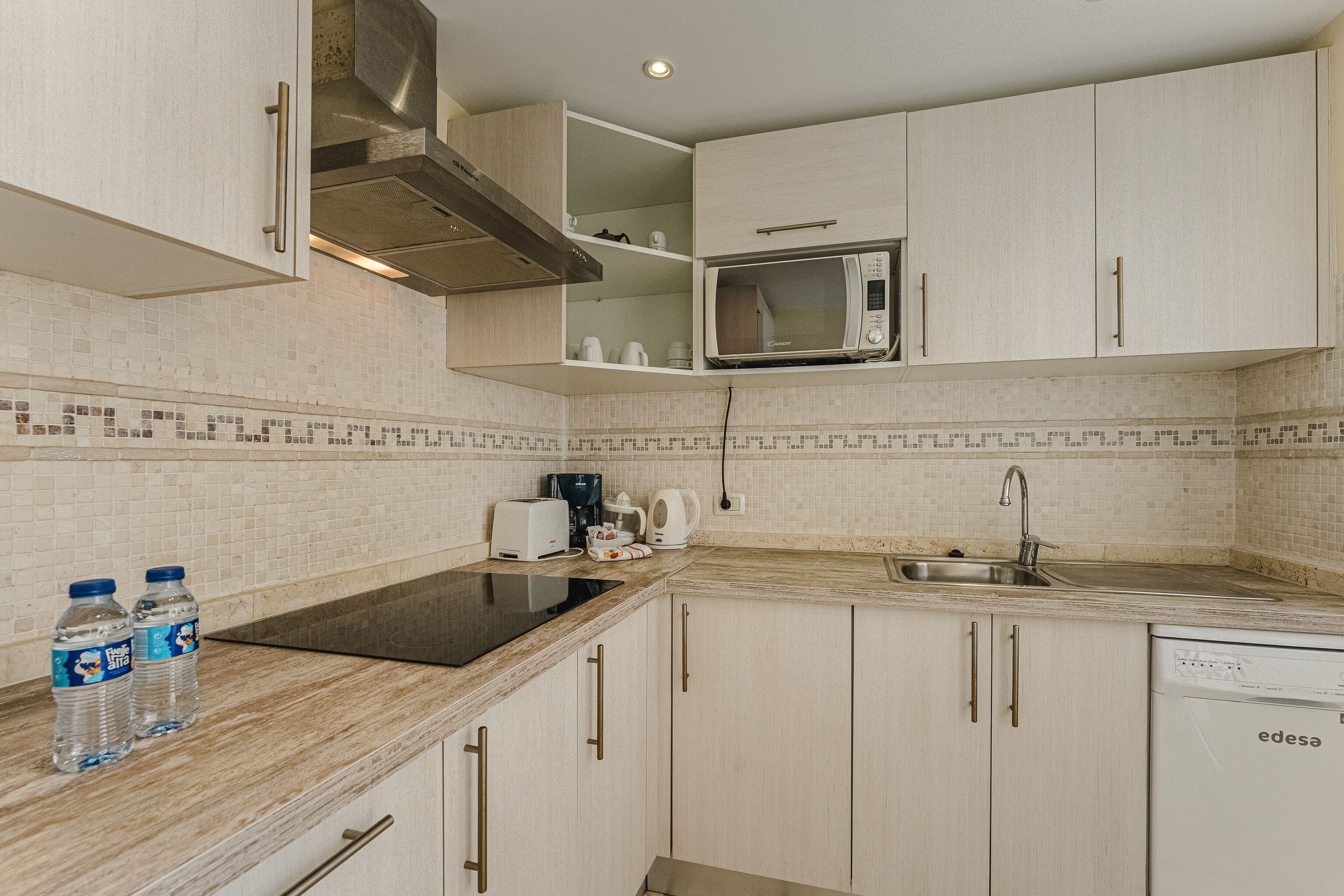 A modern kitchen with white cabinets, a microwave, a sink, and a dishwasher.