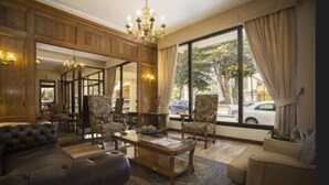 Uma sala de estar ampla com uma grande janela, um candelabro e um sofá de couro.
