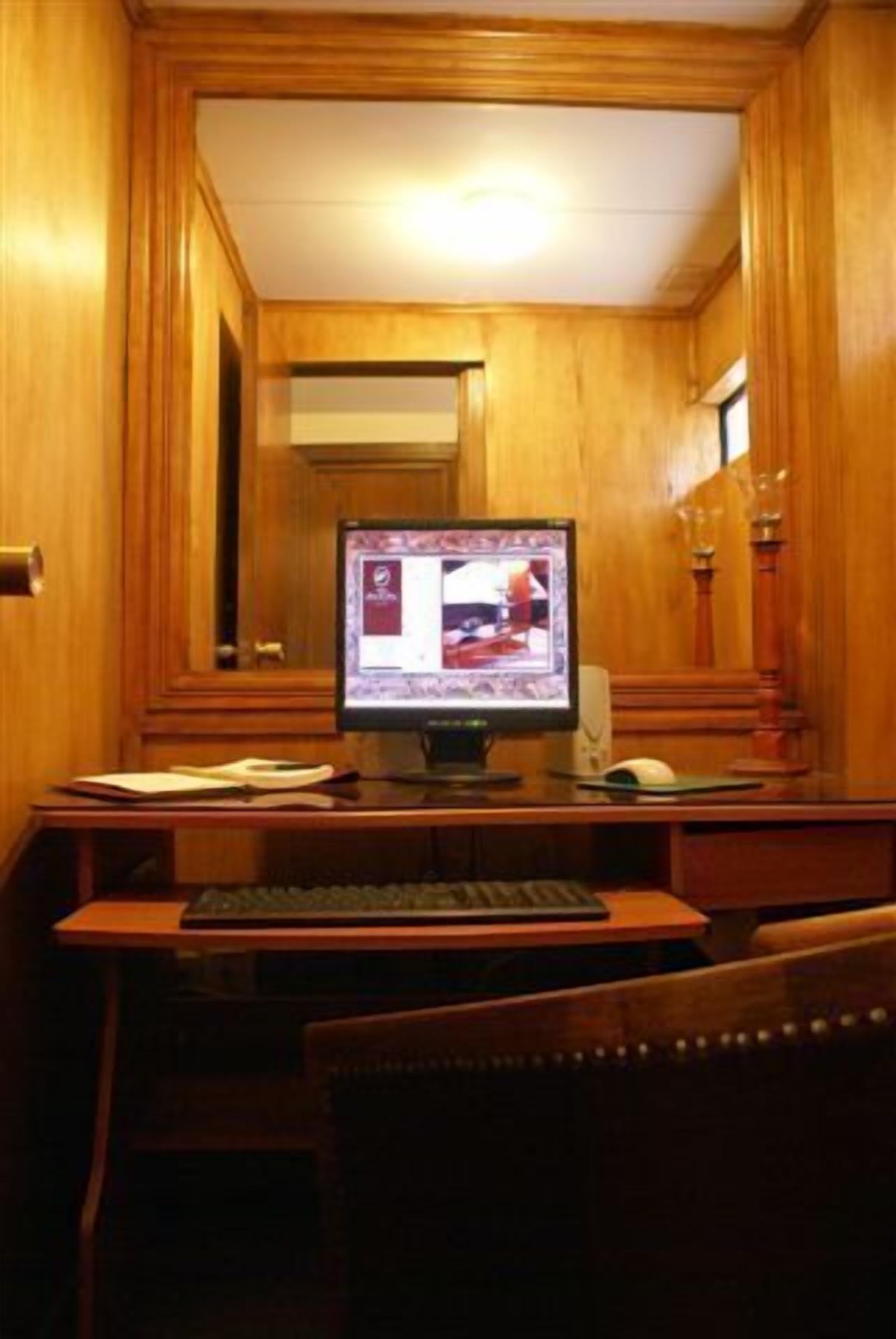 A wooden-paneled room with a desk, computer, and chair.