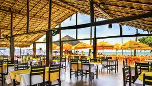 Un restaurante con terraza, mesas con manteles amarillos y sombrillas naranjas.