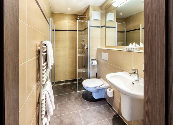 Un baño moderno con cabina de ducha de vidrio, inodoro y lavamanos.