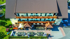 Un hotel con tejado de azulejos, zona de estar al aire libre y varios balcones con jardineras.