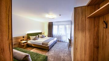 Een hotelkamer met een groot bed, een groene bank, houten wanden en een raam met gordijnen.