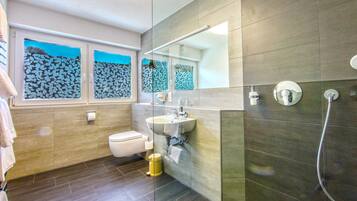Un baño moderno con inodoro, lavamanos y ducha.