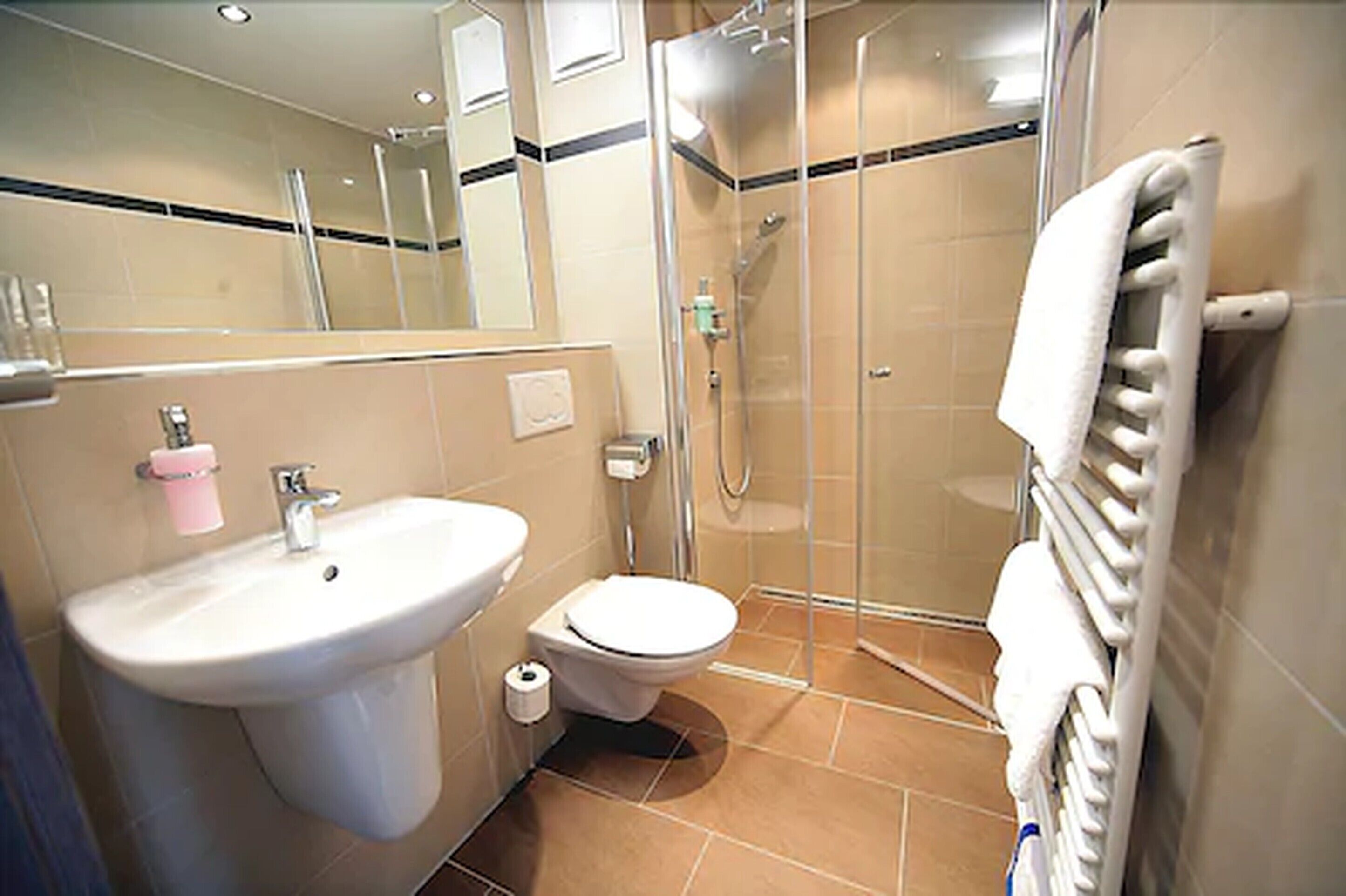 Une salle de bain équipée d’un lavabo, de toilettes, d’une douche et d’un porte-serviettes.