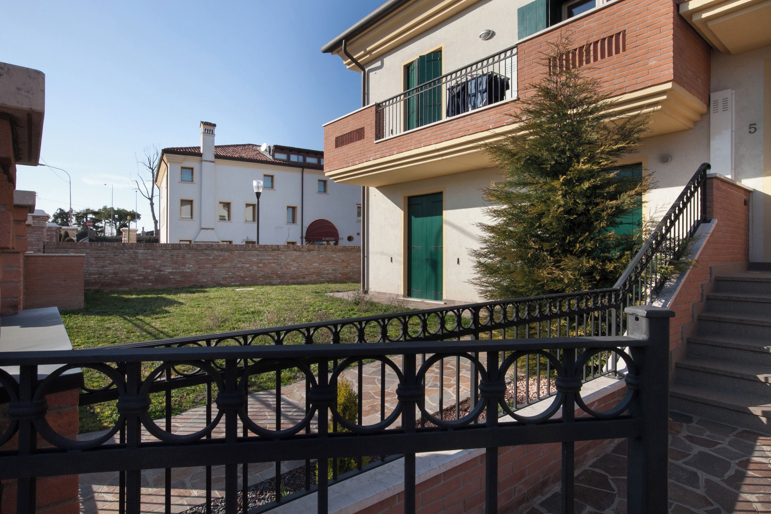Un edifici residencial amb una porta verda, un balcó i una escala de pedra.