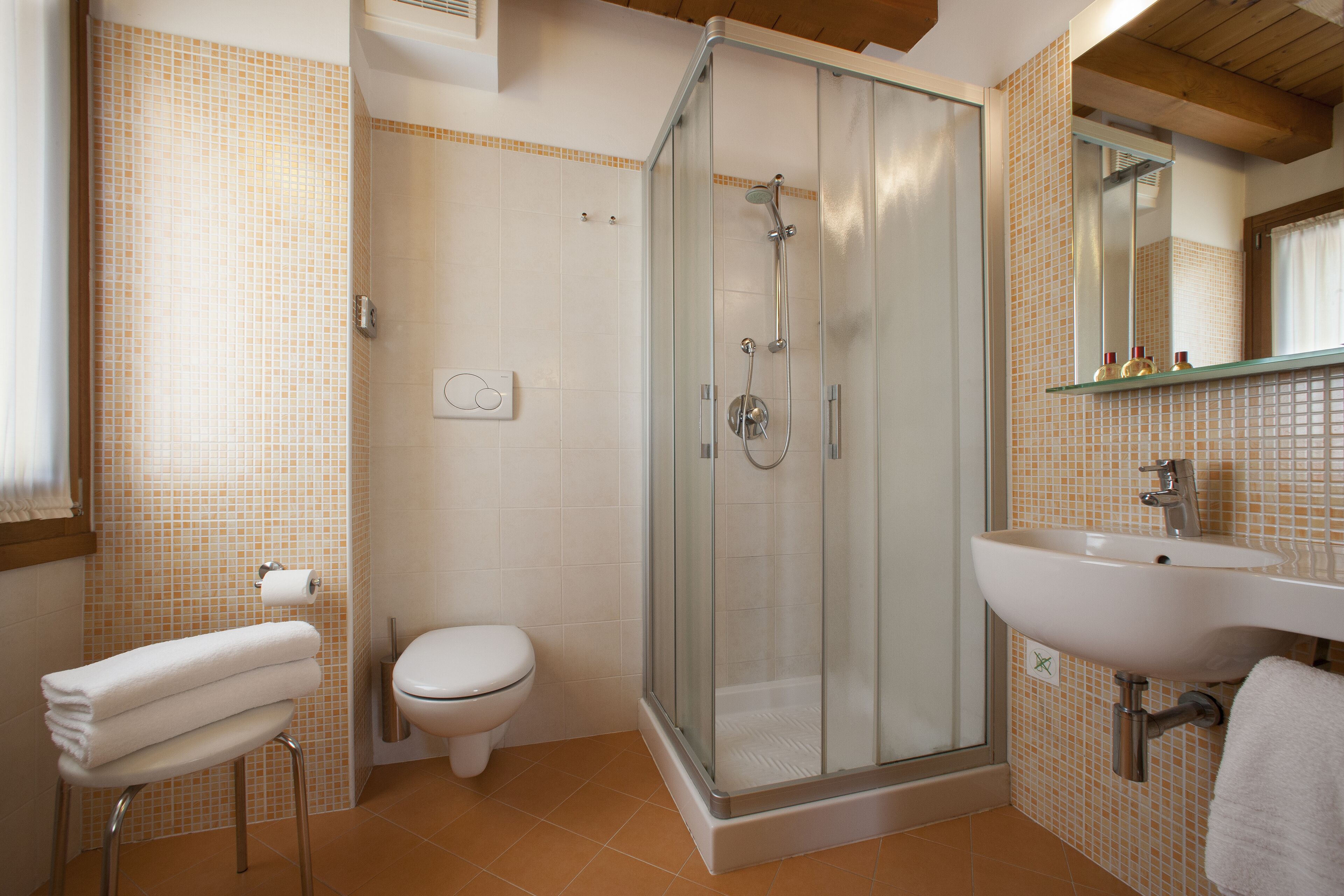 Un baño con ducha de vidrio, un lavamanos blanco y un inodoro.