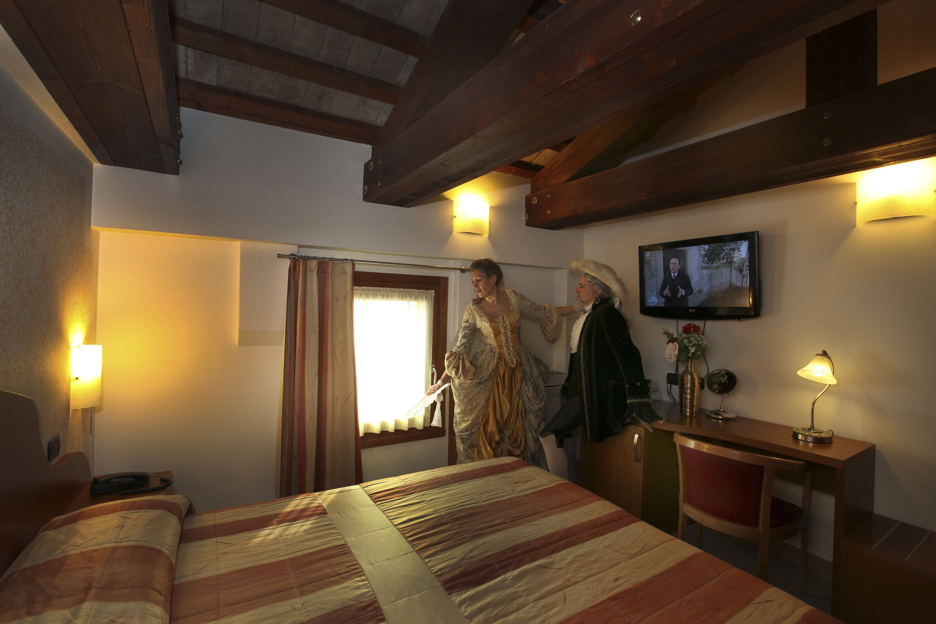 A hotel room with a bed, a desk, a television, and a window with curtains.