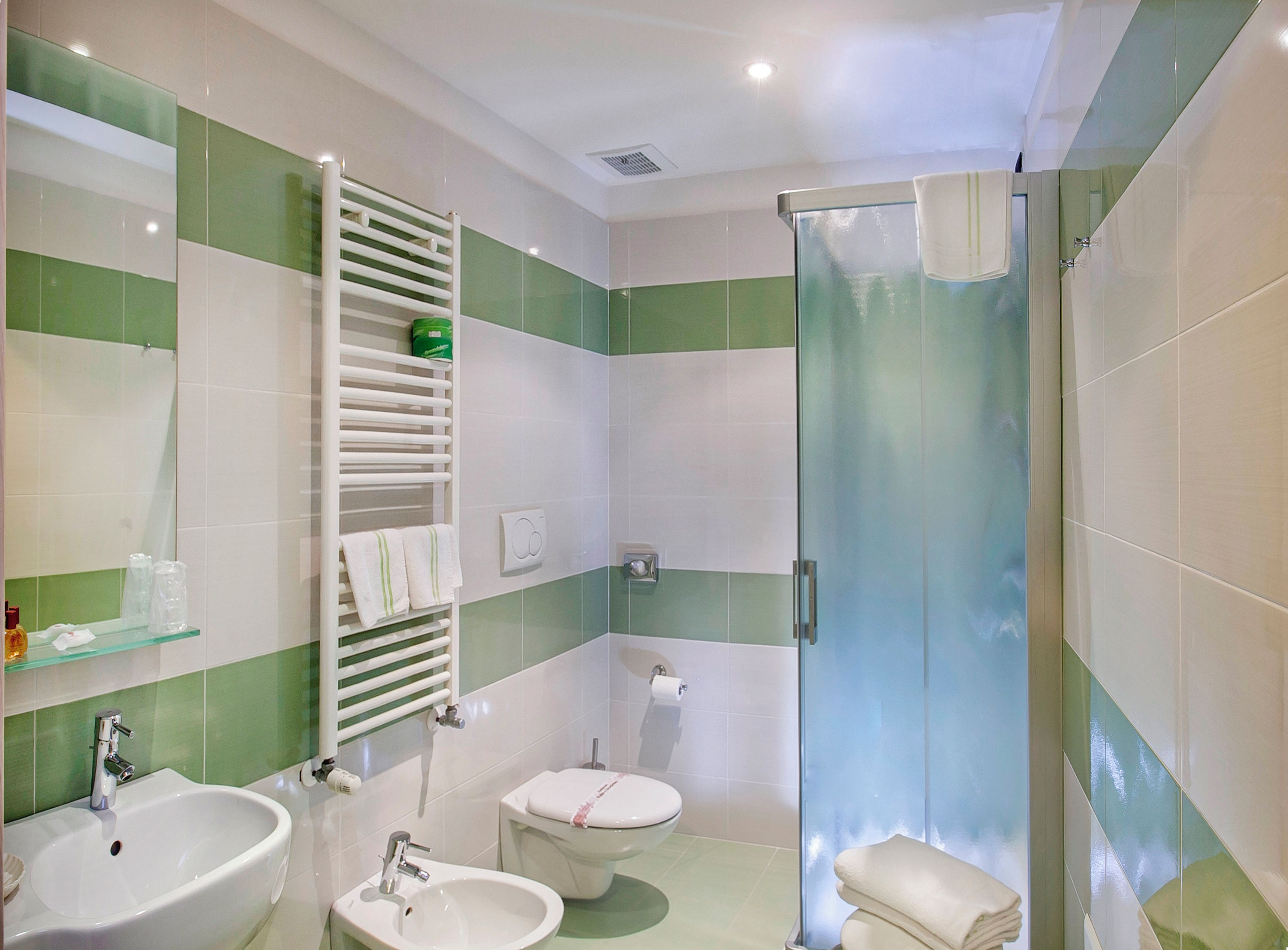 A bathroom with a glass shower enclosure, a toilet, and two sinks.