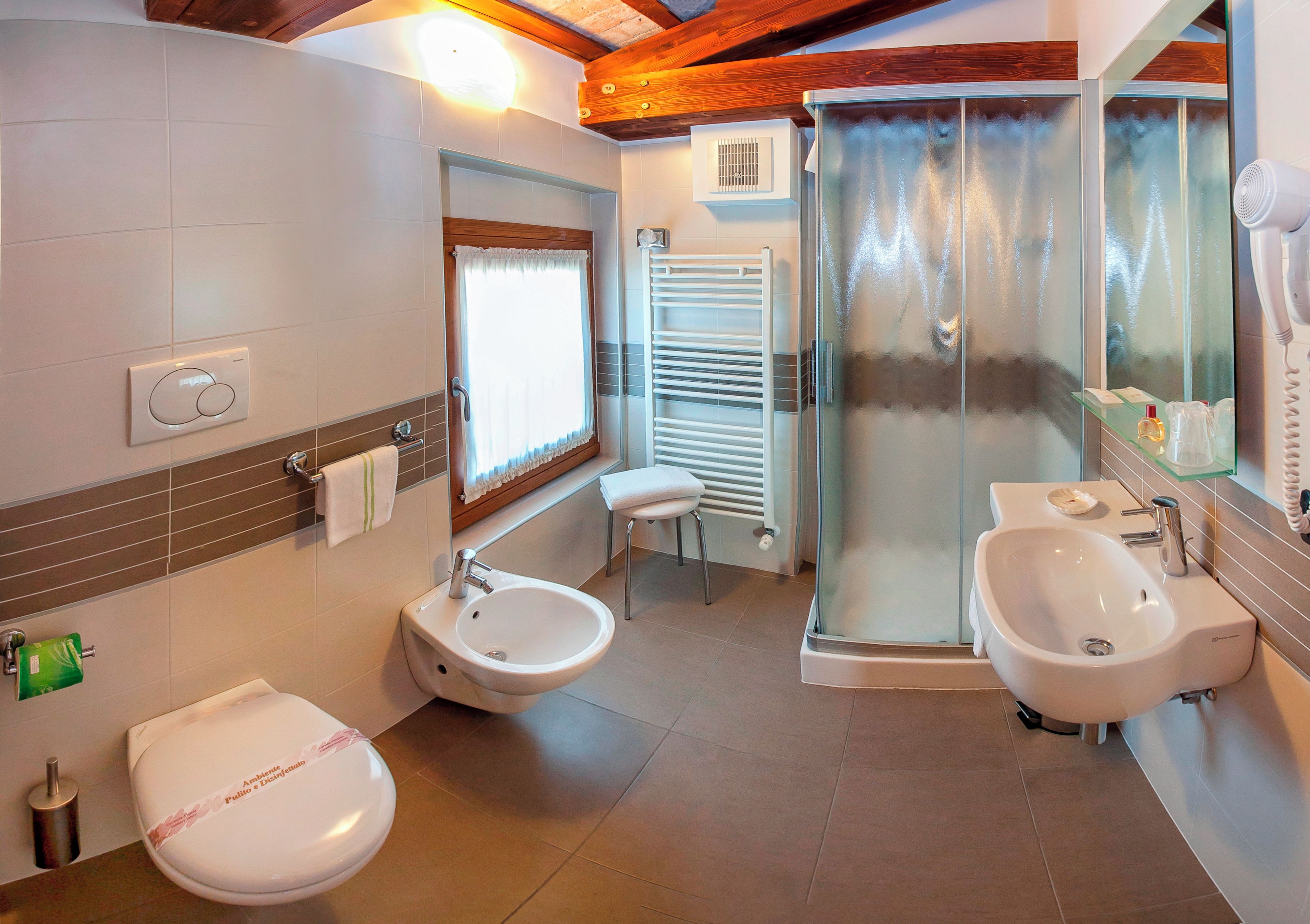Un baño con inodoro, bidé y cabina de ducha con paredes de vidrio.