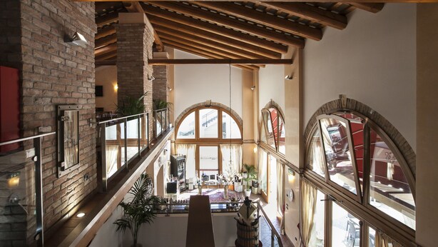 Un interior espacioso con techo alto, vigas de madera y amplios ventanales de arco que dejan entrar la luz natural.