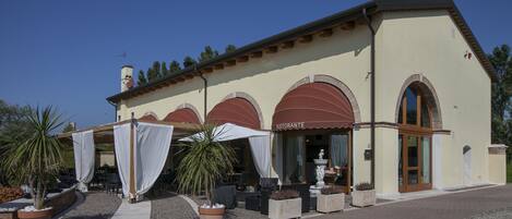 A building with a restaurant named "Ristorante" featuring outdoor seating with umbrellas and potted plants.