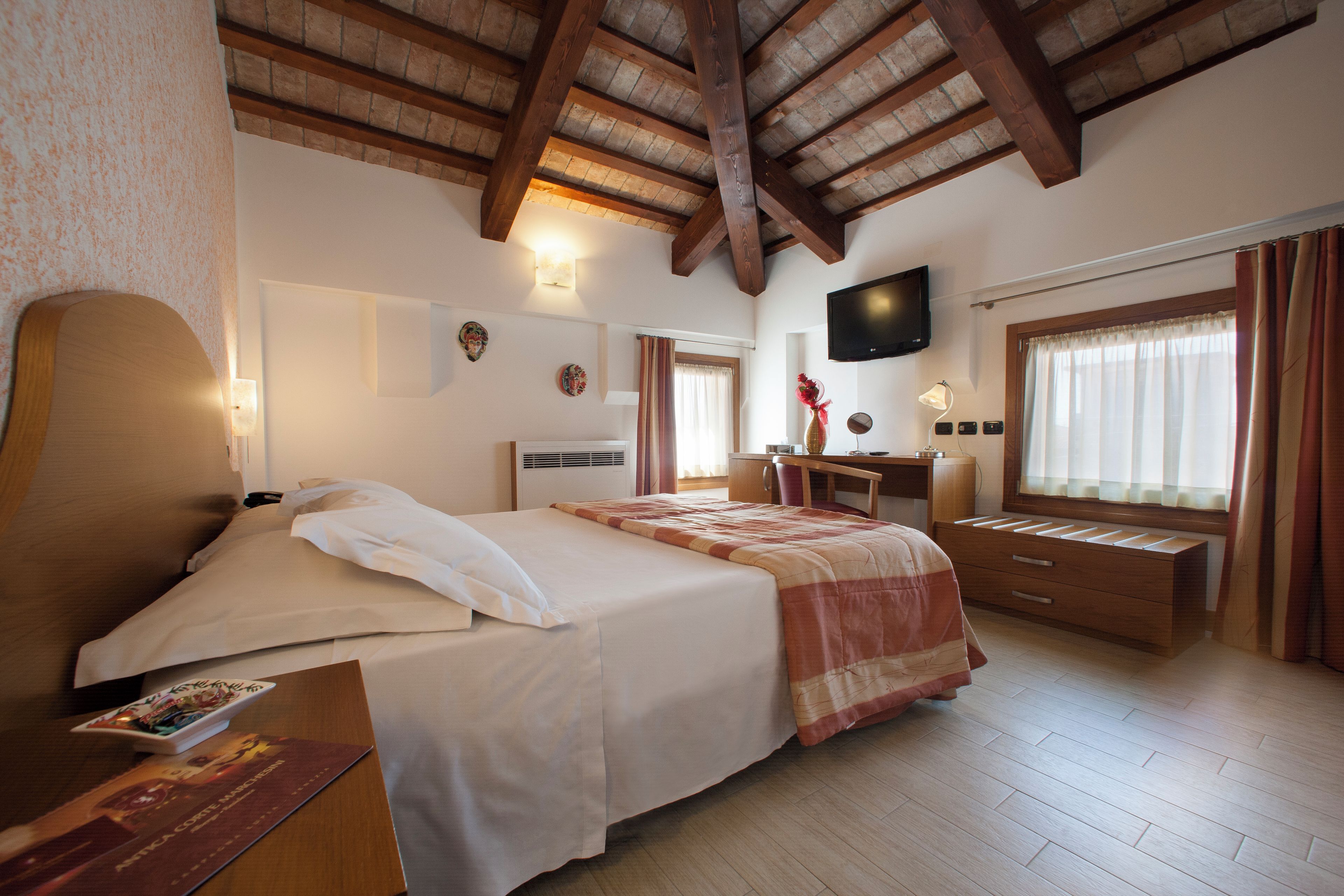 Een hotelkamer met een bed, een bureau, een televisie en een raam met gordijnen.