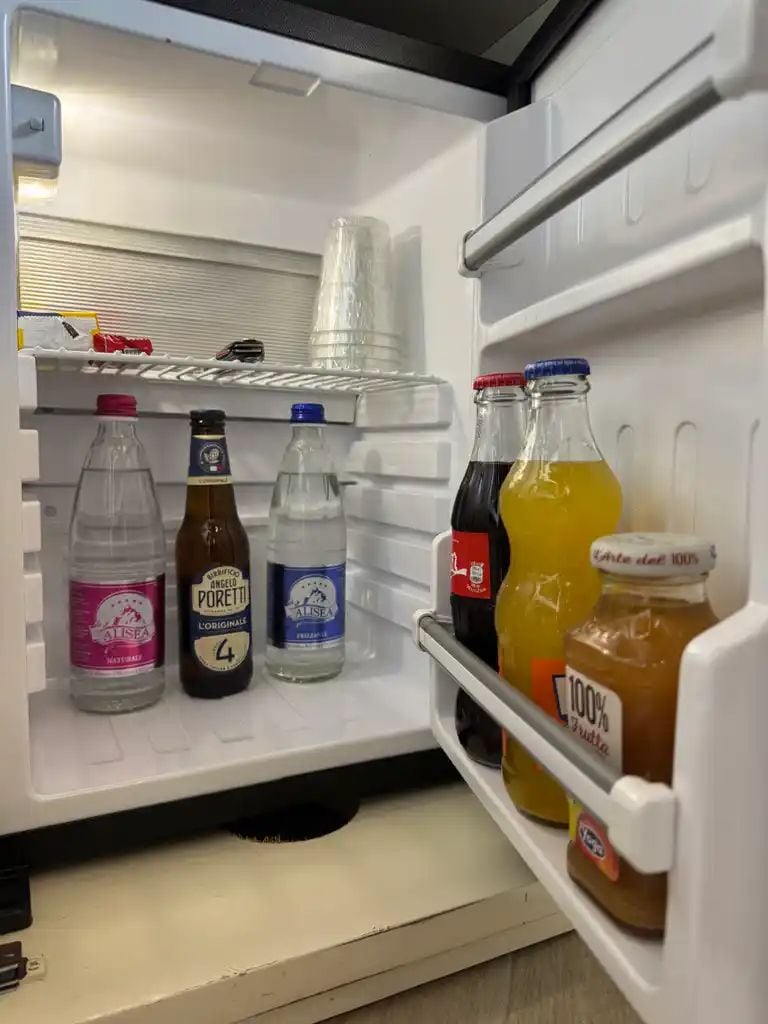 A refrigerator with bottles of water, beer, and juice.