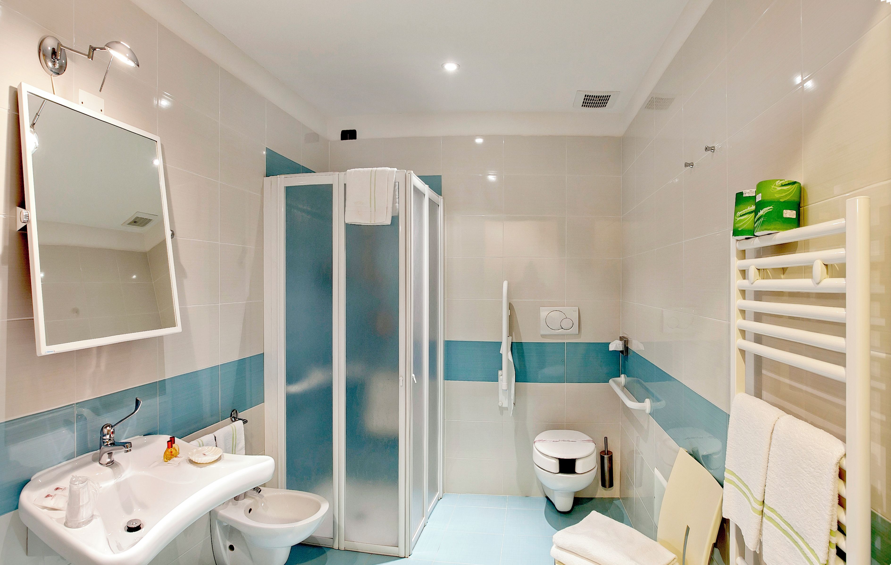 Un baño moderno con cabina de ducha, lavamanos, inodoro y espejo.