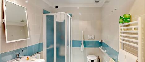 Un baño moderno con cabina de ducha, lavamanos, inodoro y espejo.