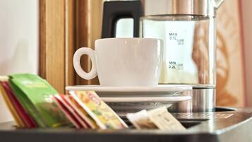 Une machine à café avec une tasse et une soucoupe blanches, un sac de café vert et un livre sur une table.