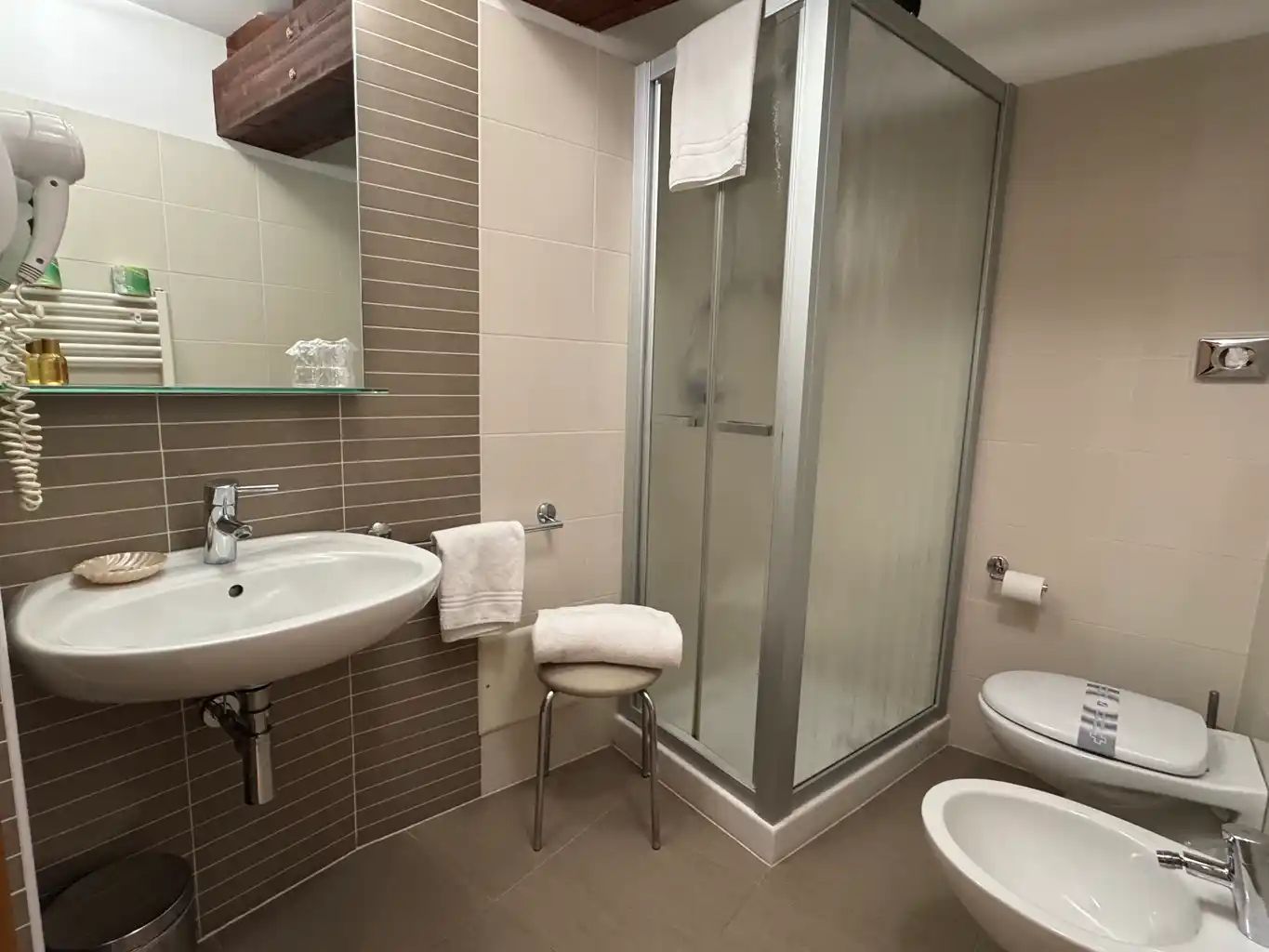 A bathroom with a glass-enclosed shower, a sink, and a toilet.