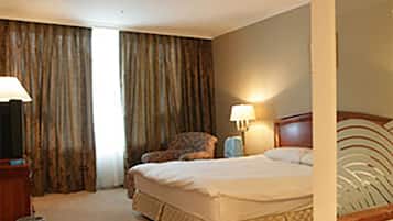 Una habitación de hotel con una cama grande, una silla, un escritorio y una lámpara.