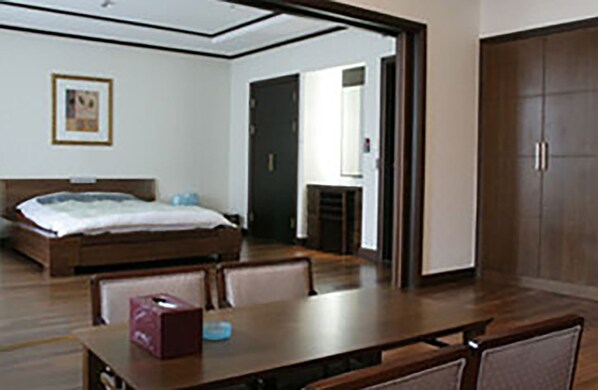 A hotel room with a bed, a desk, and a chair. There is a door leading to another room and a window. - High1 Palace Hotel & CC (Jeongseon)