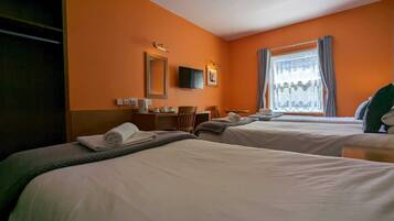 A hotel room with two beds, a desk, a chair, a TV, and a window with curtains.