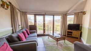 A living room with a sofa set, a coffee table, and a television. - Embleton Spa Hotel (Cockermouth)