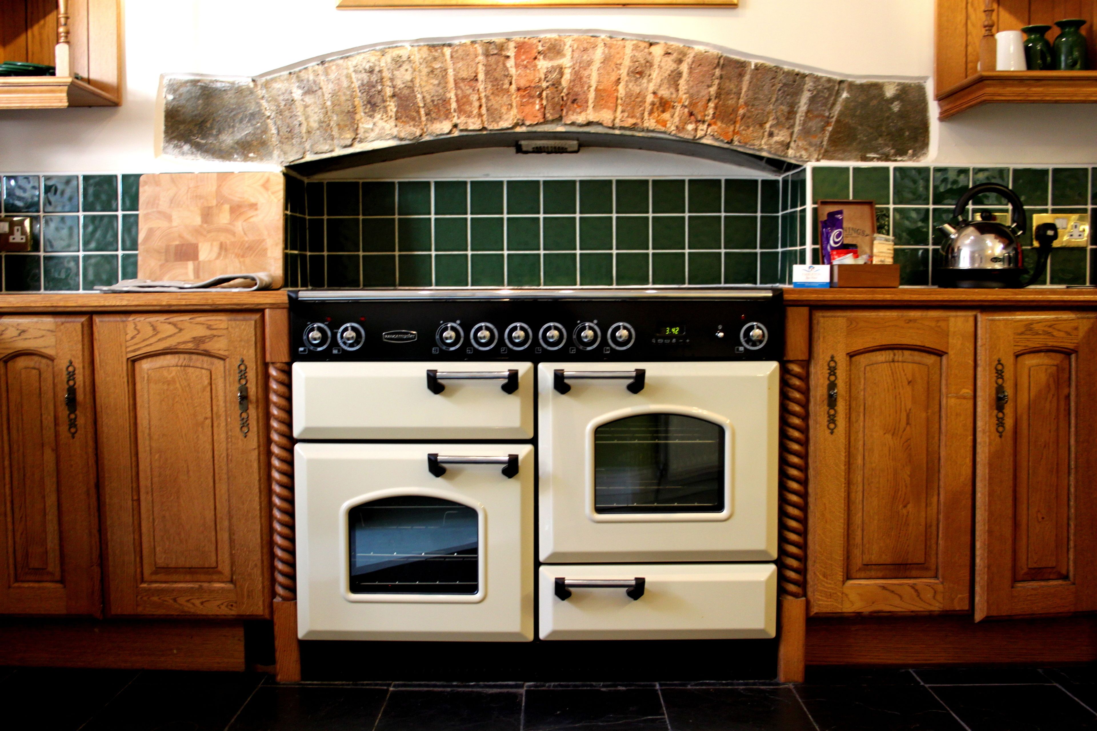 A kitchen with a double oven, wooden cabinets, and a tiled backsplash.