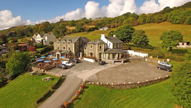 A large, historic stone building with multiple wings, a central courtyard, and a parking area. - Embleton Spa Hotel (Cockermouth)