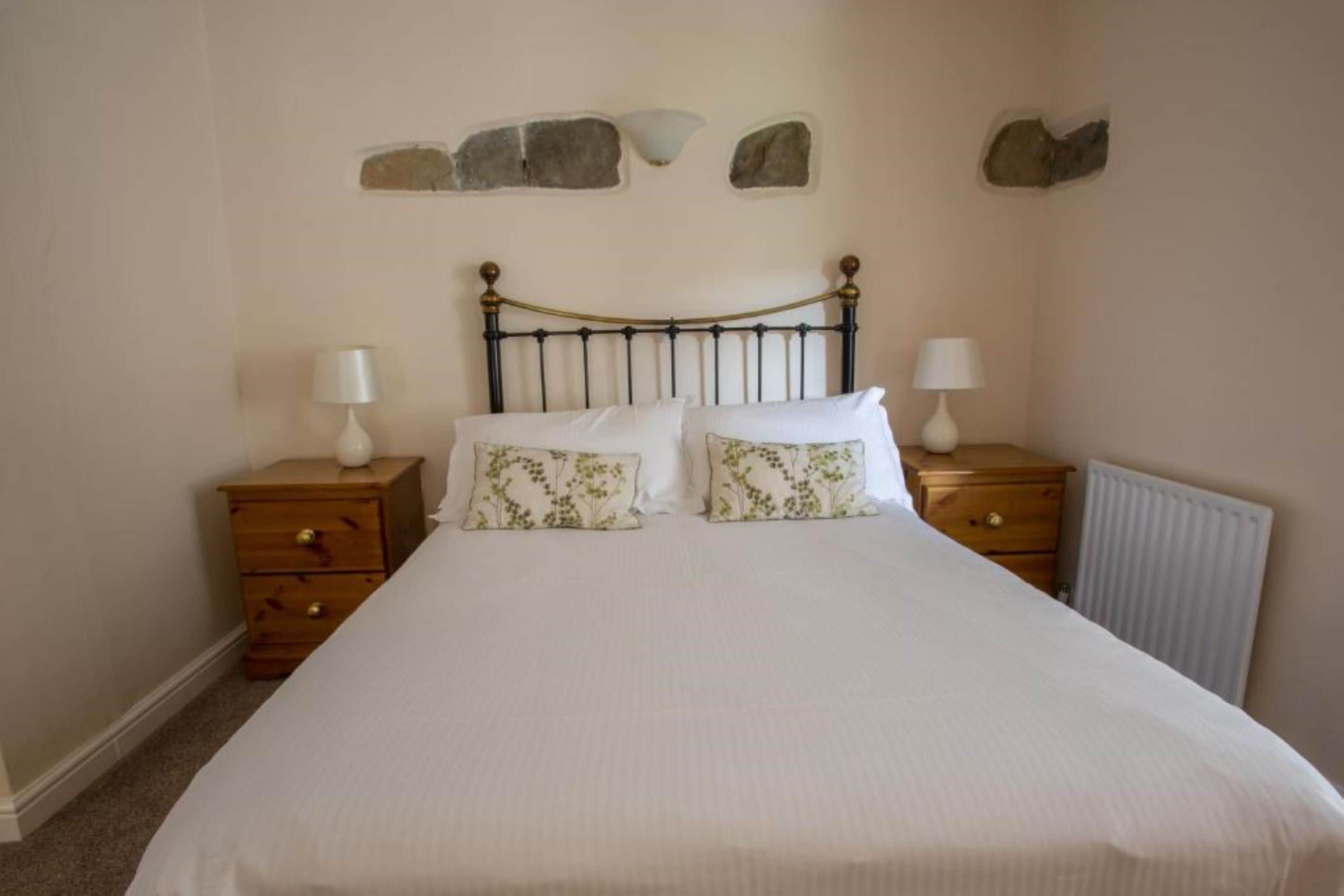 A bedroom with a bed, two nightstands, and a radiator.