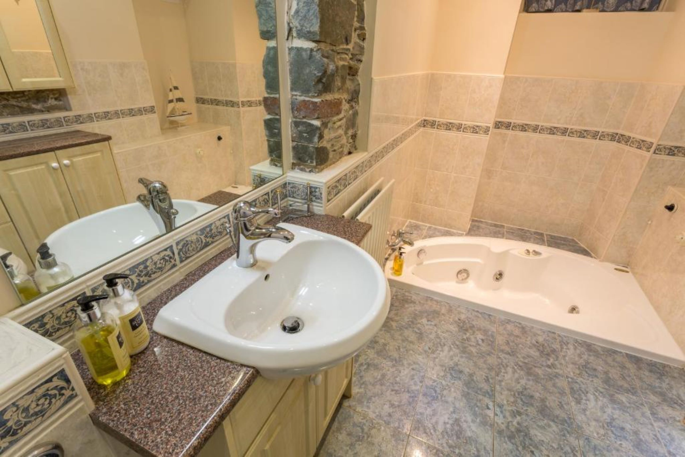A bathroom with a sink, mirror, and bathtub.