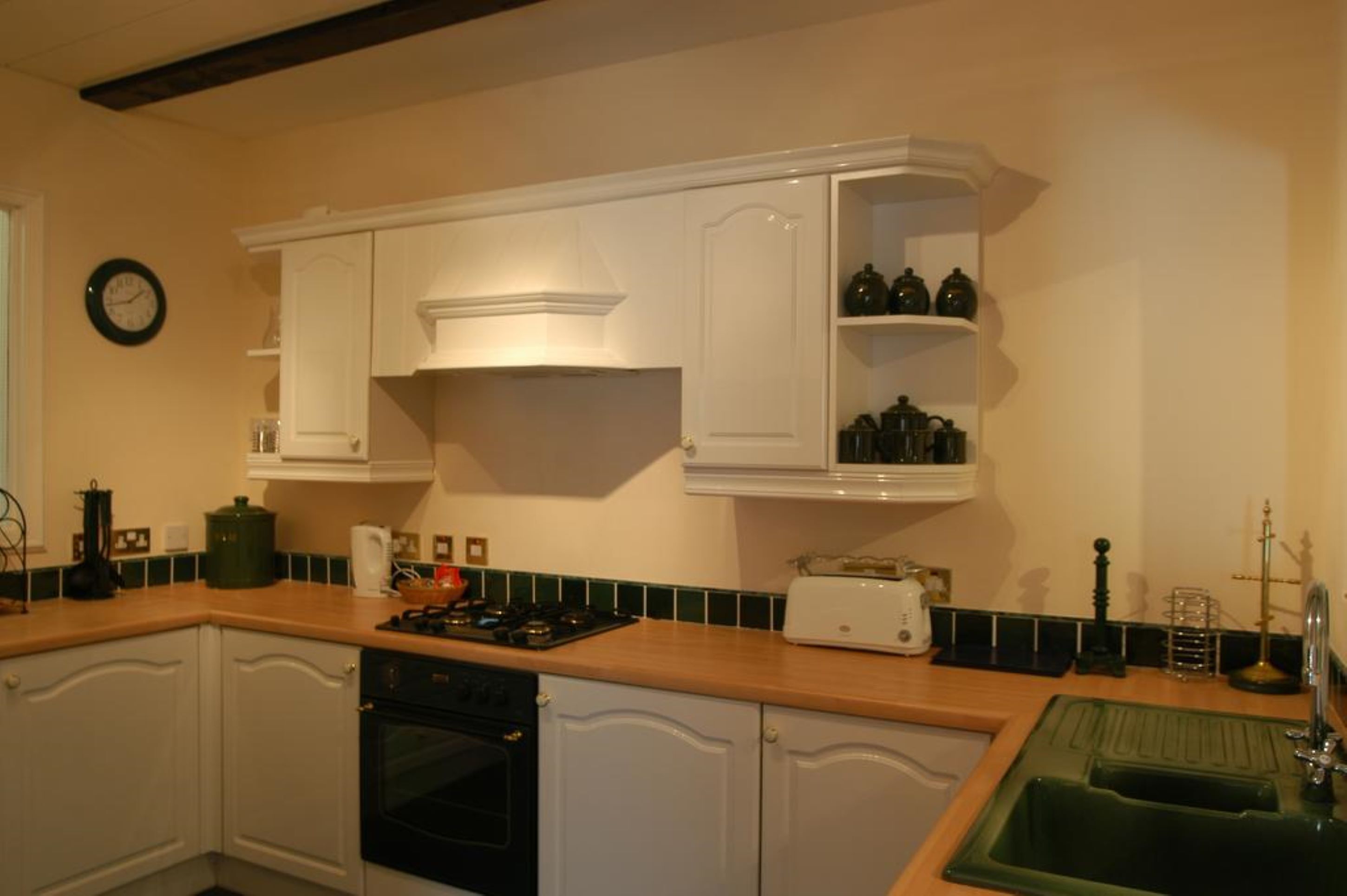 A kitchen with white cabinets, a stove, a dishwasher, and a green sink.