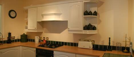 A kitchen with white cabinets, a stove, a dishwasher, and a green sink.