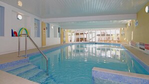 An indoor swimming pool with clear blue water, a metal ladder, and tiled steps leading into the pool. - Embleton Spa Hotel (Cockermouth)