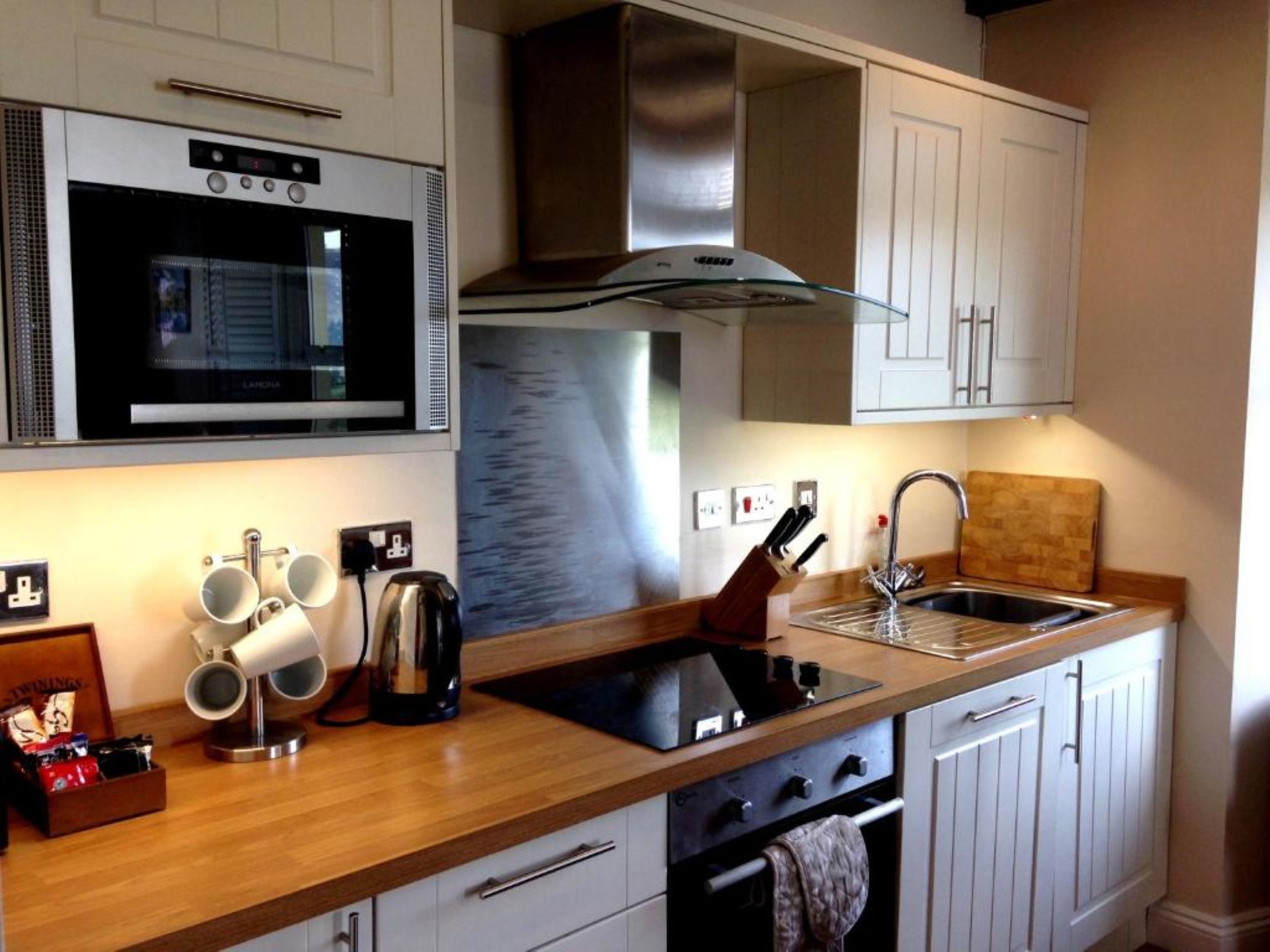 A modern kitchen with stainless steel appliances, wooden countertops, and white cabinetry.