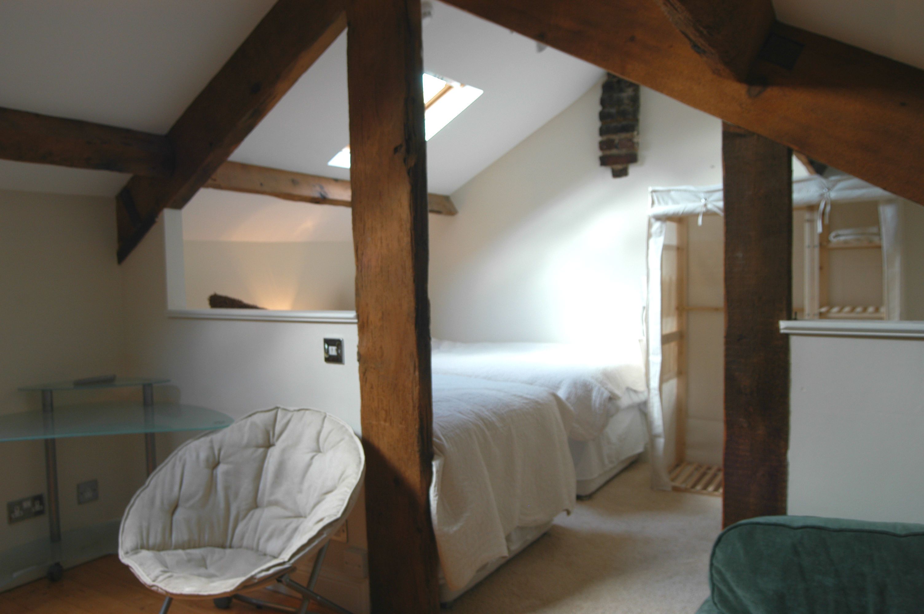 A room with a loft bed, a glass table, and a chair.