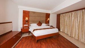 A hotel room with a wooden bed, bedside tables, and a headboard with built-in lighting. - Hotel Trinity Isle (Bengaluru)